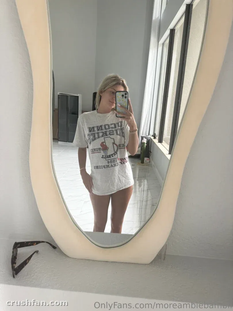 Créatrice en t-shirt graphique blanc prenant un selfie dans le miroir dans une pièce lumineuse