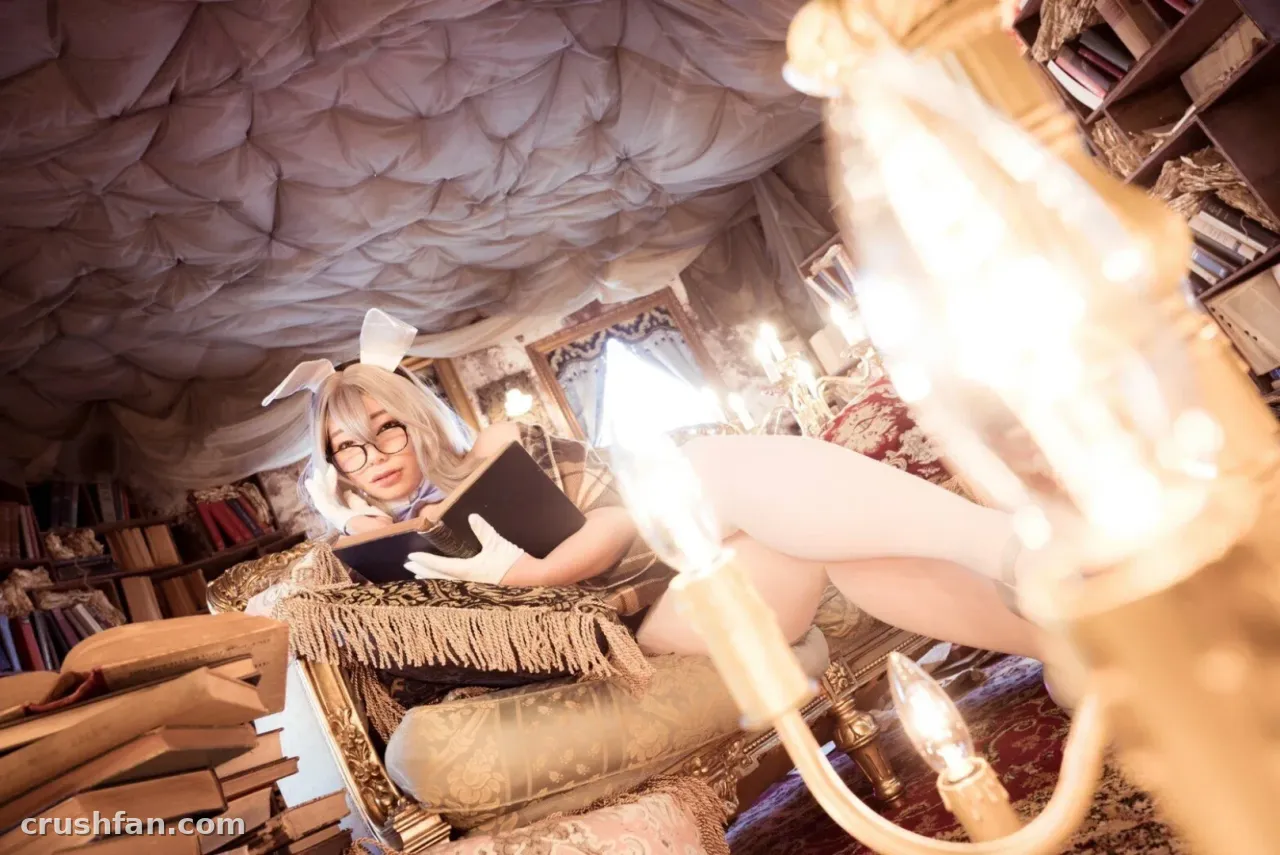 Tunamayo sits in an armchair with a book, wearing bunny ears and glasses in a cozy library.