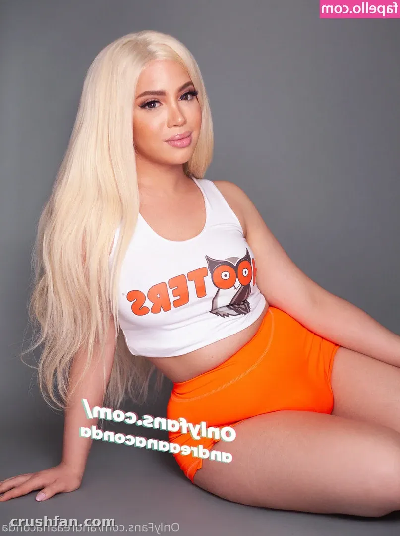 Creator seated on a grey studio backdrop in a white crop top and orange shorts
