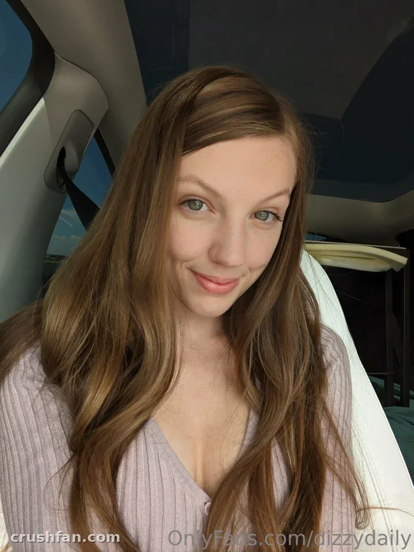 Créatrice en haut côtelé lilas souriant dans un selfie sur un siège de voiture.