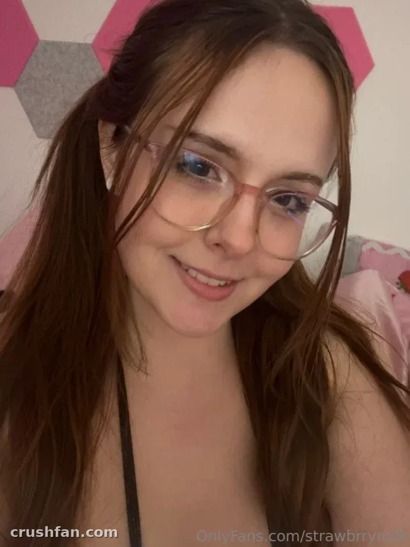 Strawbrrymilk smiling in glasses and a black top indoors