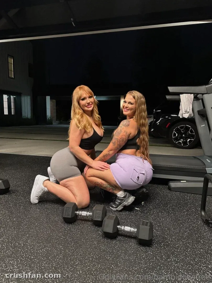 Bambi Doe kneeling in a home gym beside a friend with dumbbells on the floor