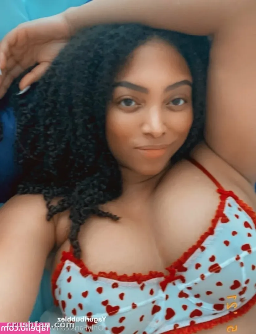 Creator in a blue heart print camisole with red trim, resting an arm behind her head.