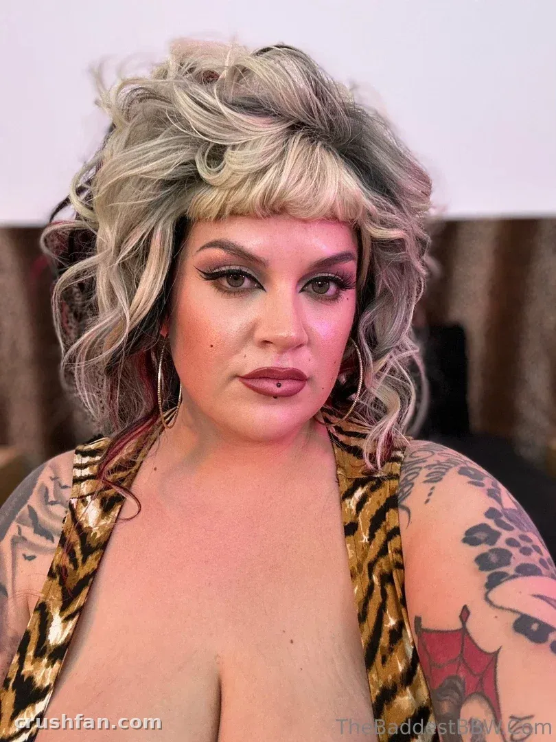 Marilyn Mayson em uma blusa de estampa animal com cabelo loiro ondulado e maquiagem ousada