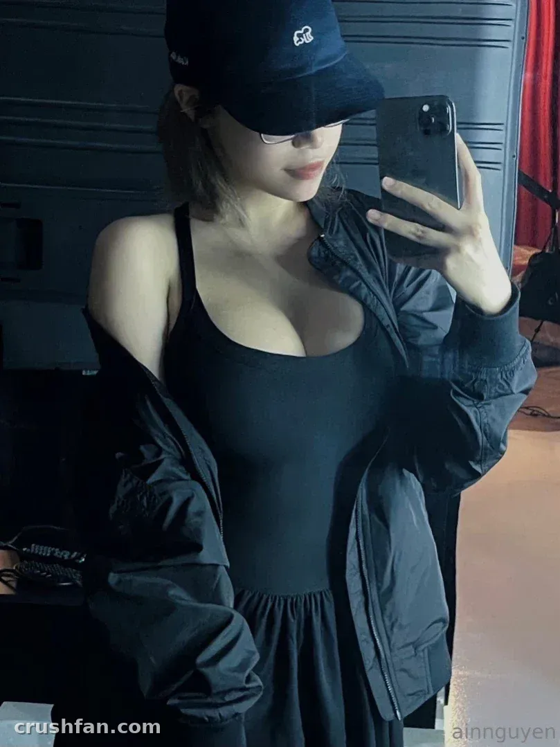 Ain Nguyen prenant un selfie dans le miroir avec une tenue entièrement noire, une casquette et des lunettes.