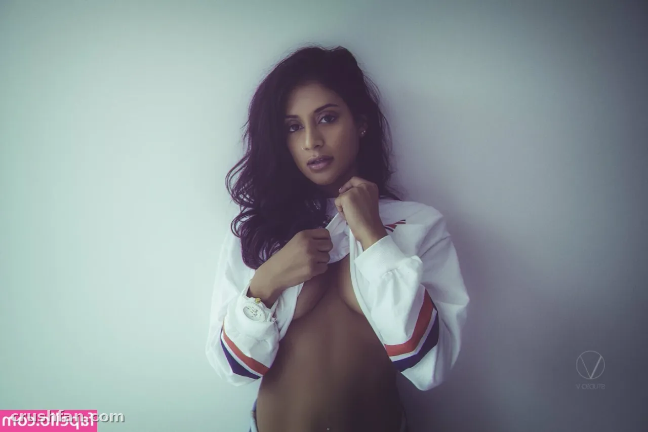 Woman in a white striped jacket posing against a plain wall