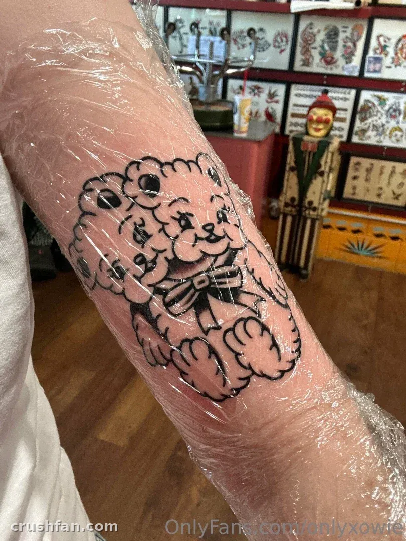 Frisches Teddybär-Tattoo auf einem Unterarm, in klare Plastikfolie gewickelt, in einem Tattoostudio.