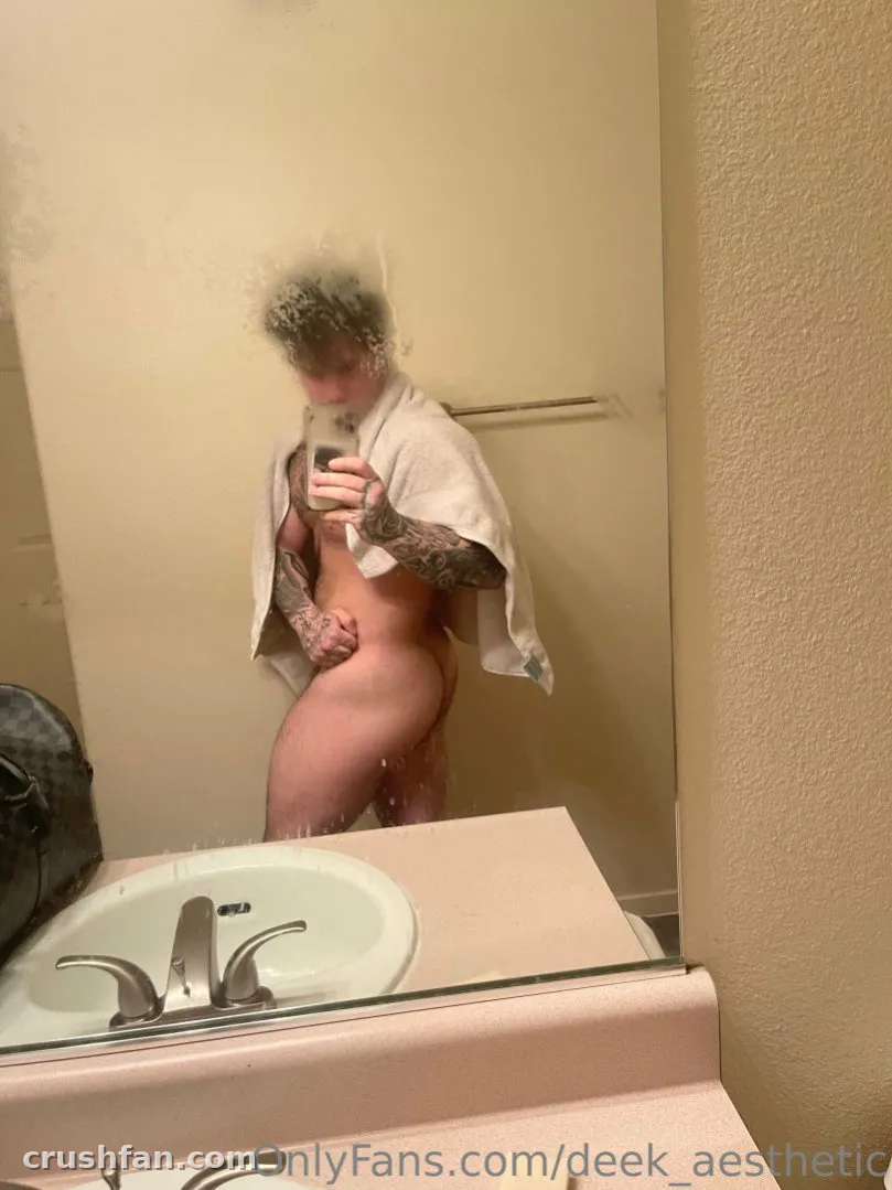 DEEK AESTHETIC taking a mirror selfie in a bathroom while wrapped in a towel.