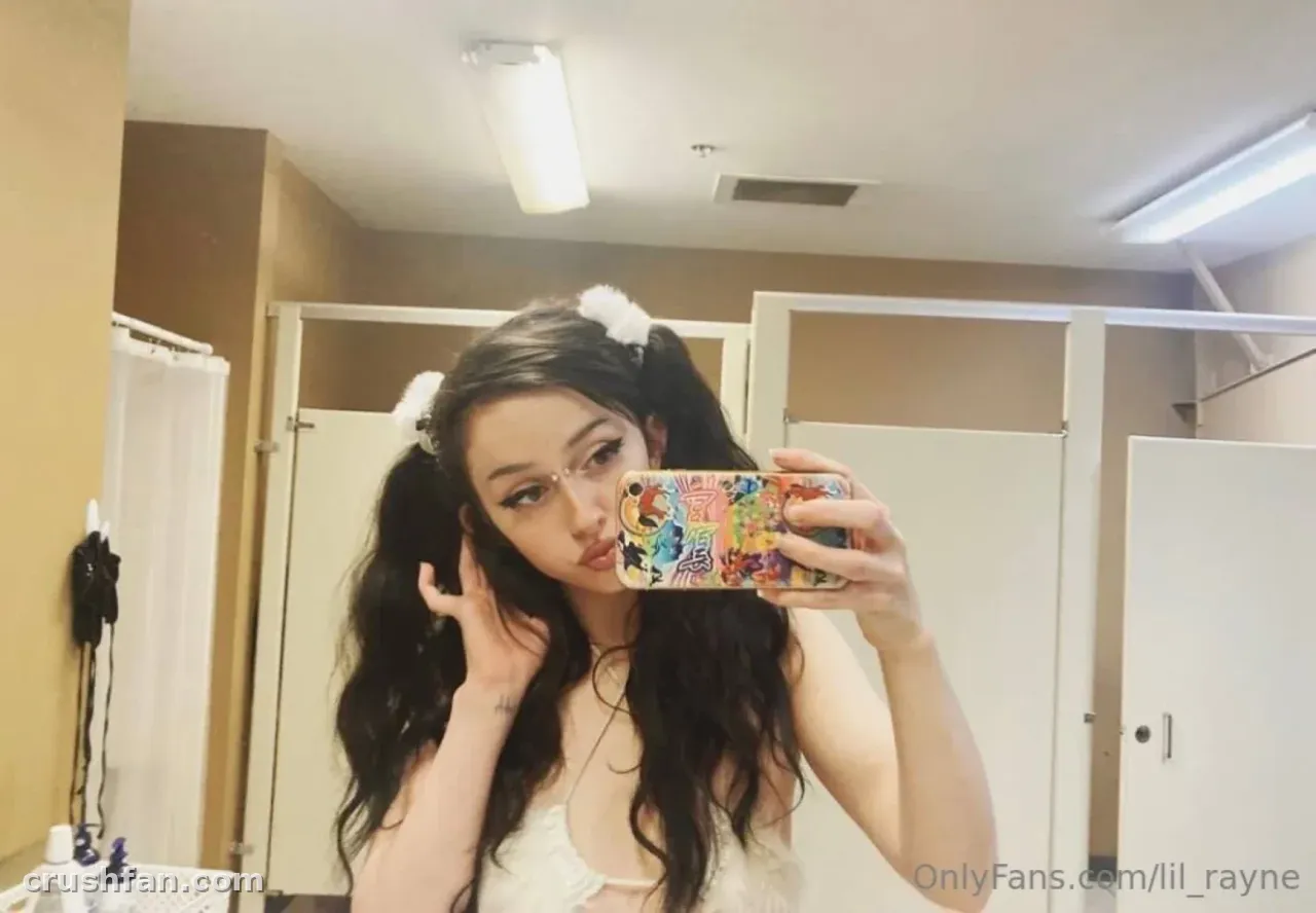 Creator with dark pigtails and white scrunchies taking a mirror selfie in a restroom
