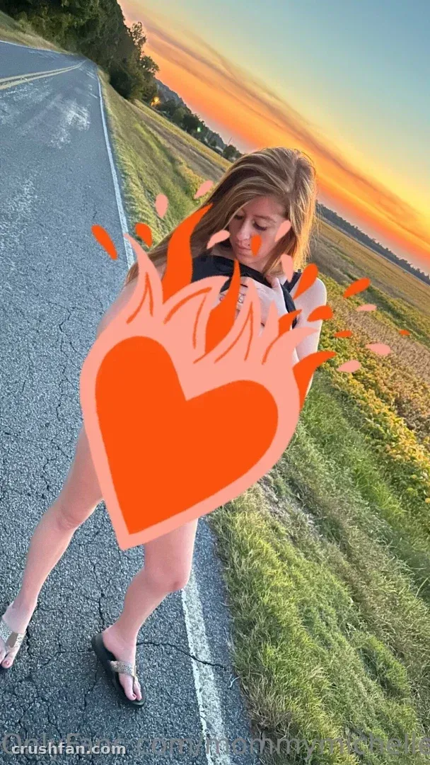 Creator standing on a country road at sunset with a large orange heart graphic over the frame