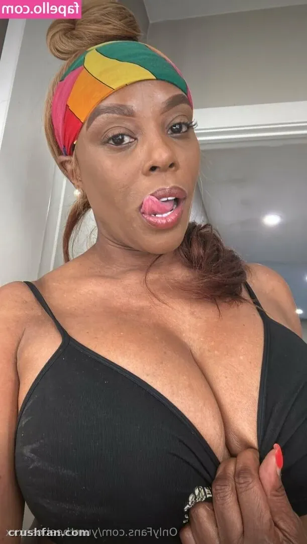 Creator in a black top and multicoloured headwrap taking an indoor close-up selfie