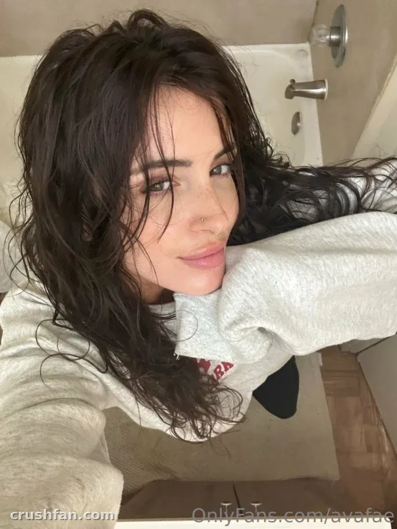 Ava Ruru taking a selfie in a grey sweatshirt inside a bathroom.