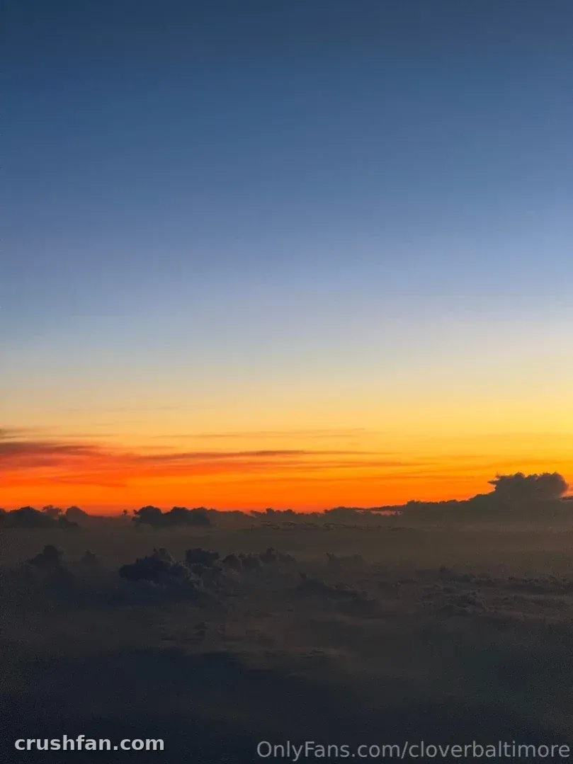 Vivid orange and blue sunset sky above a misty, dark field at dusk