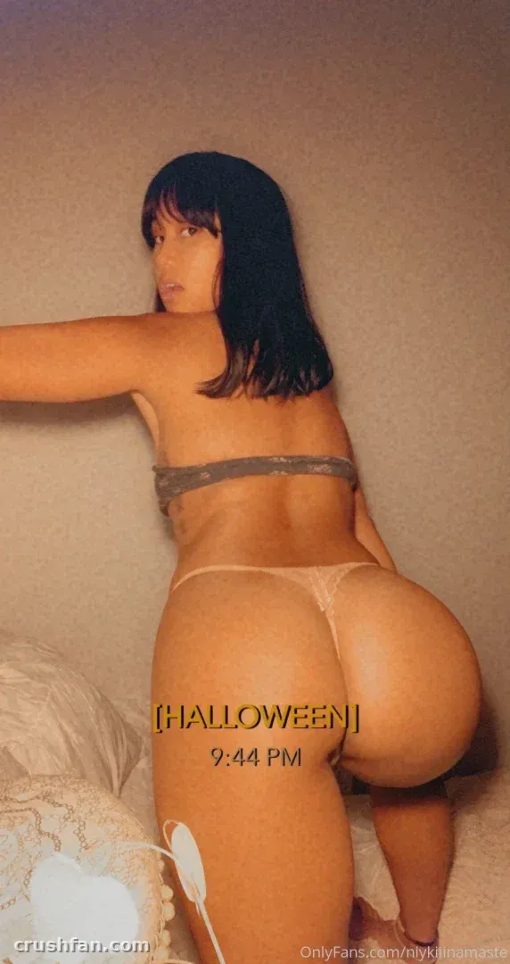 Angel Love in grey lingerie looking back over her shoulder in a dim room