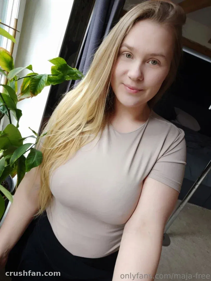 Maja-Meer in a beige top standing by a window with a green plant