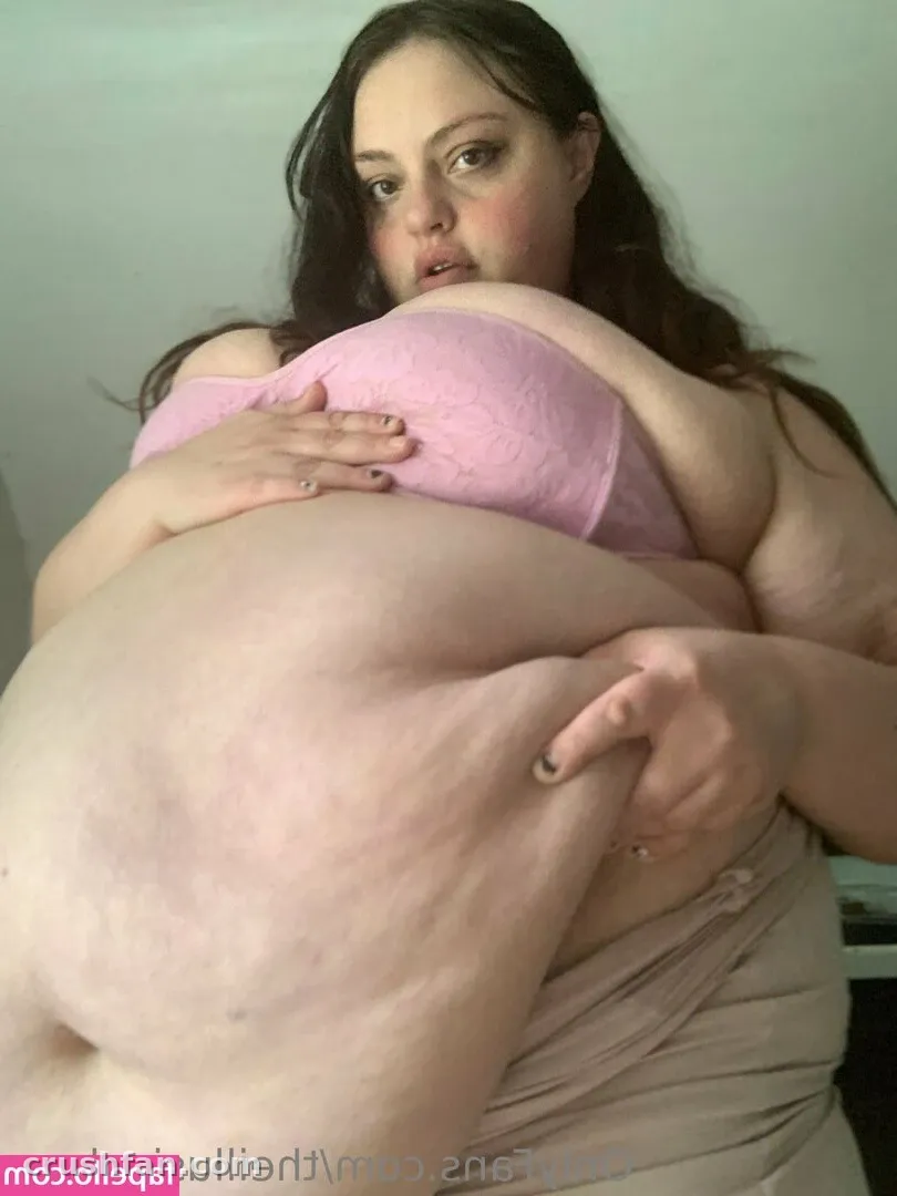 Sabrina en intérieur portant un haut rose et un drapé beige, regardant vers l'objectif