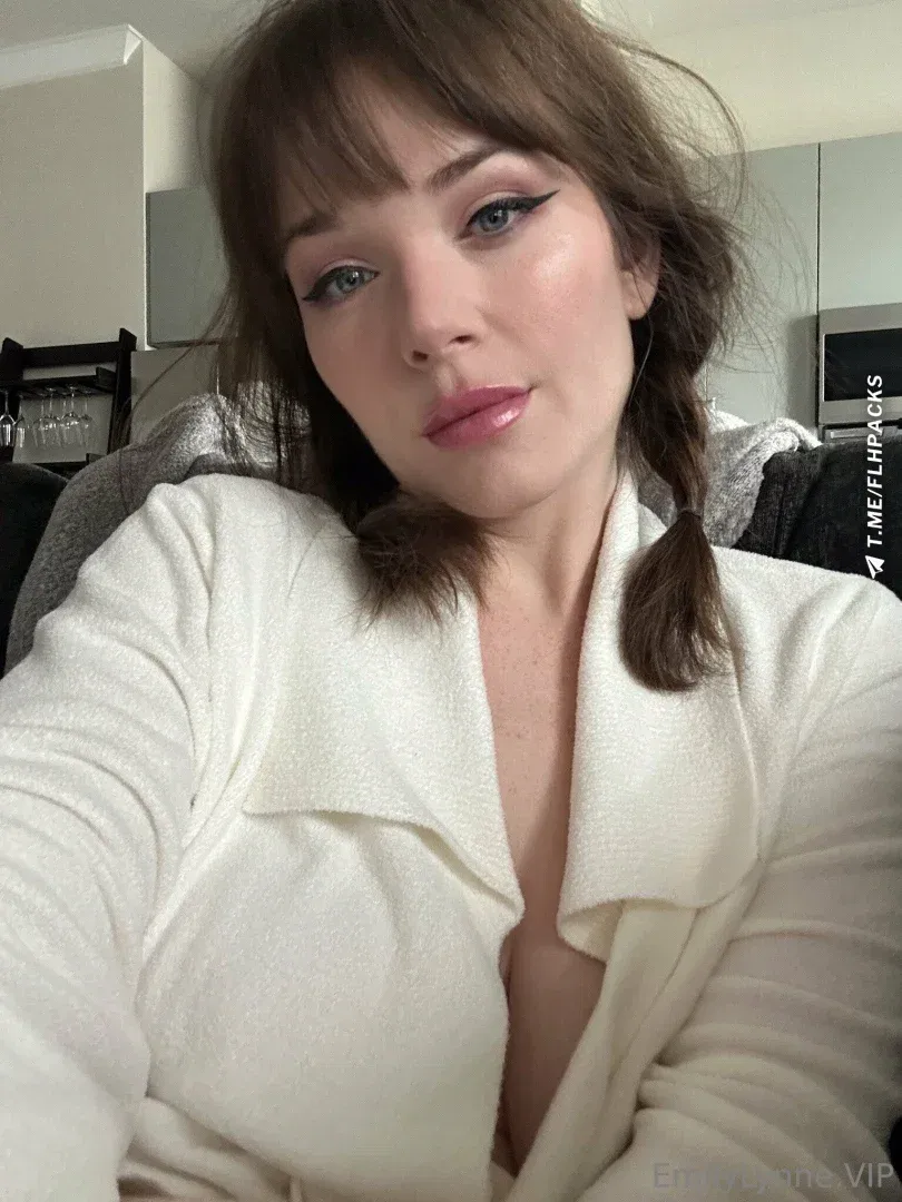 Emily Lynne in a cream blouse with braided hair indoors
