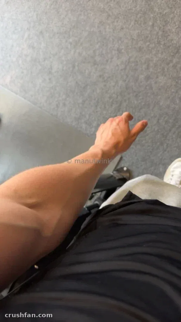 Vue rapprochée du bras de Manu étendu sur un tissu sombre rayé devant un mur gris texturé