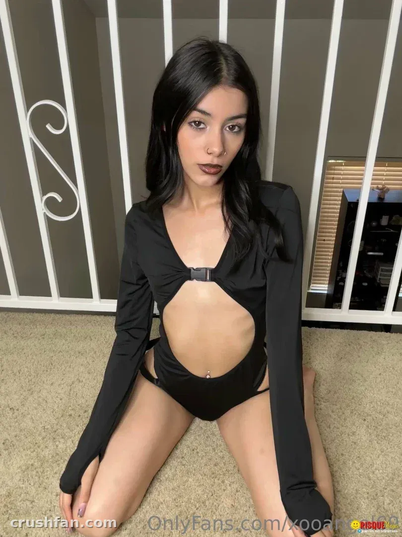 Angel baby in a black cutout bodysuit kneeling on beige carpet indoors