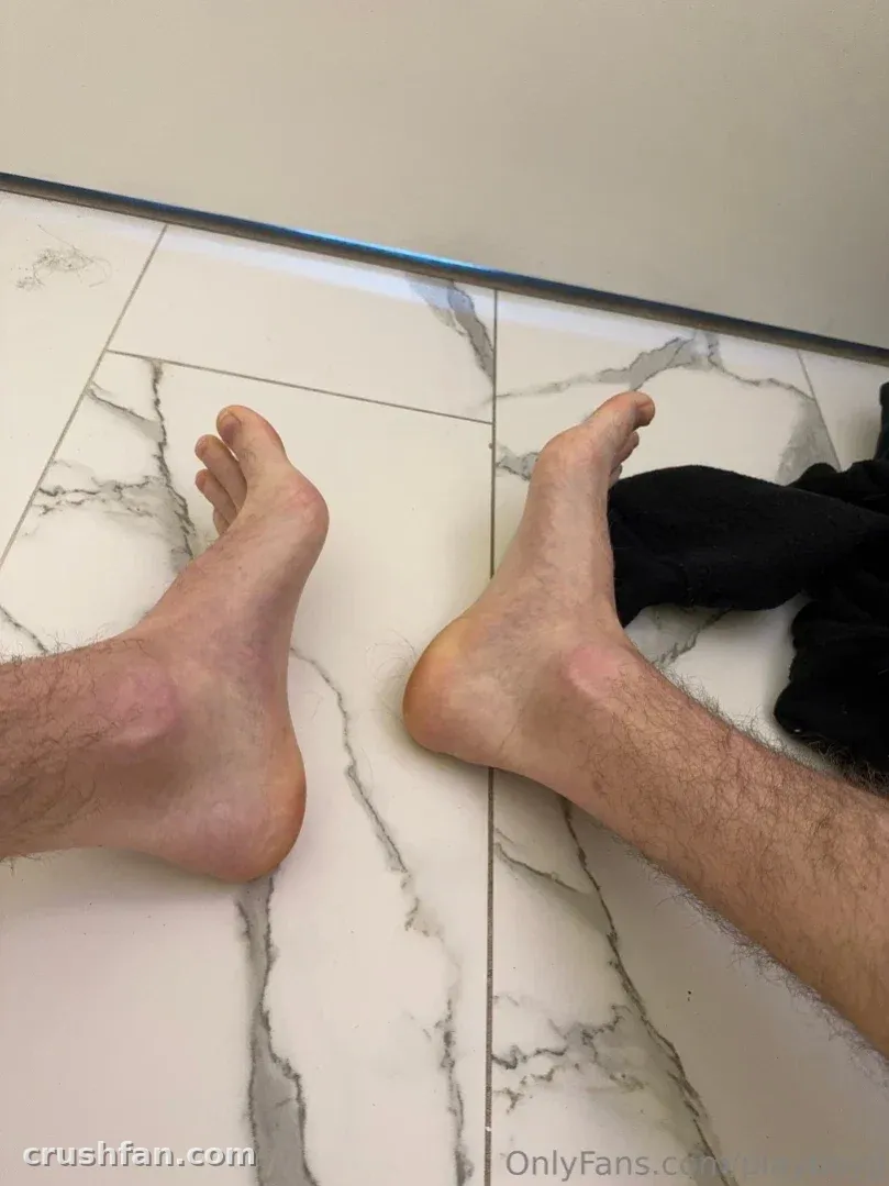 Jaydens nackte Füße ruhen auf einem weißen marmorierten Boden mit dunklem Stoff in der Nähe.
