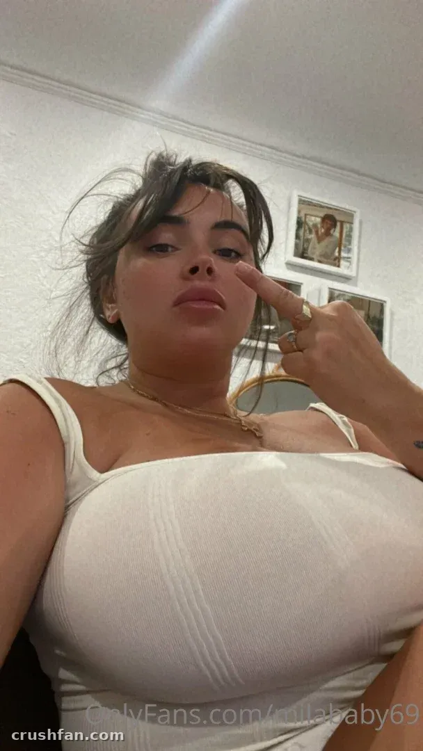 Mila ☆ Baby con un top acanalado blanco tocándose la nariz en una selfie de interior
