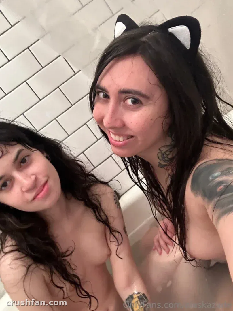Alaska Zade em um banheiro azulejado usando orelhas de gato, sorrindo com uma amiga