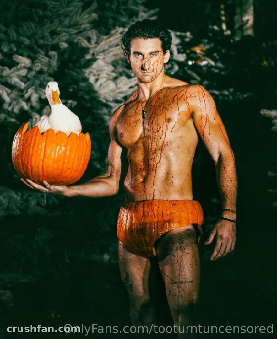Too Turnt Tony holding a carved pumpkin with a white bird inside, wearing orange briefs outdoors.
