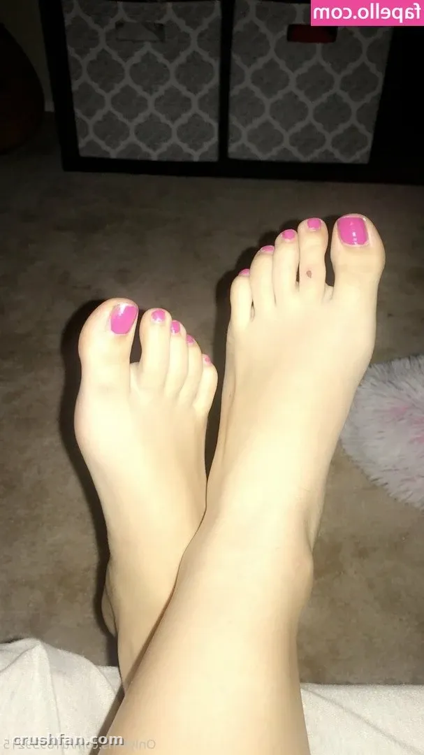 Close-up of bare feet with pink toenail polish resting on a carpet indoors