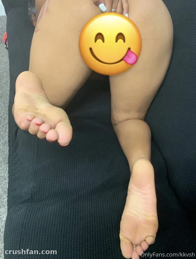 Kkvsh assise sur un canapé sombre avec un grand emoji souriant couvrant le centre du cadre