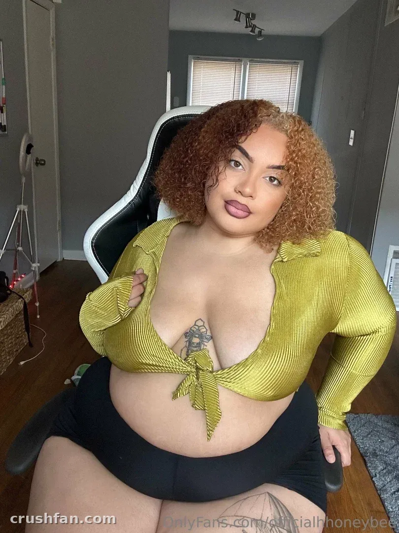 Honey dans une chemise nouée vert citron assise sur une chaise gaming noire à l'intérieur