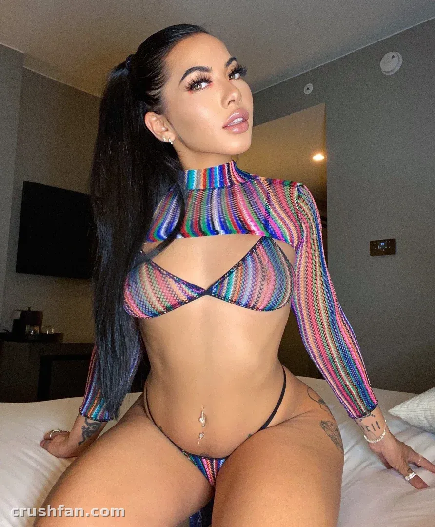 Creator in a multicoloured striped two-piece set seated on a bed in a softly lit room