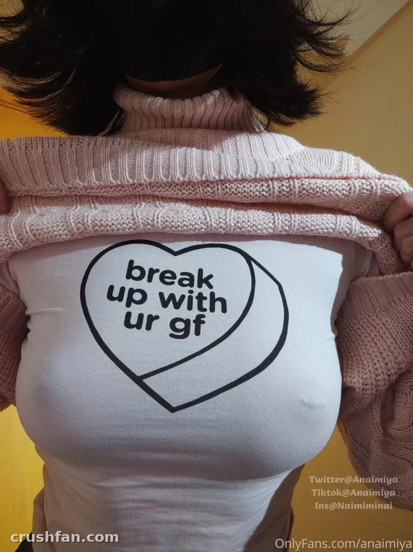 Naimi奶咪 seen from behind in a white heart-print top and pink knit cardigan against a yellow wall.