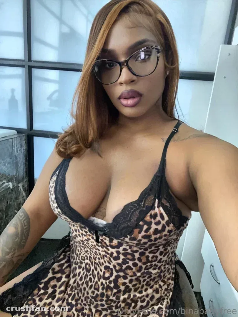 Sabrina Lynn in a leopard print slip dress and glasses taking an indoor selfie