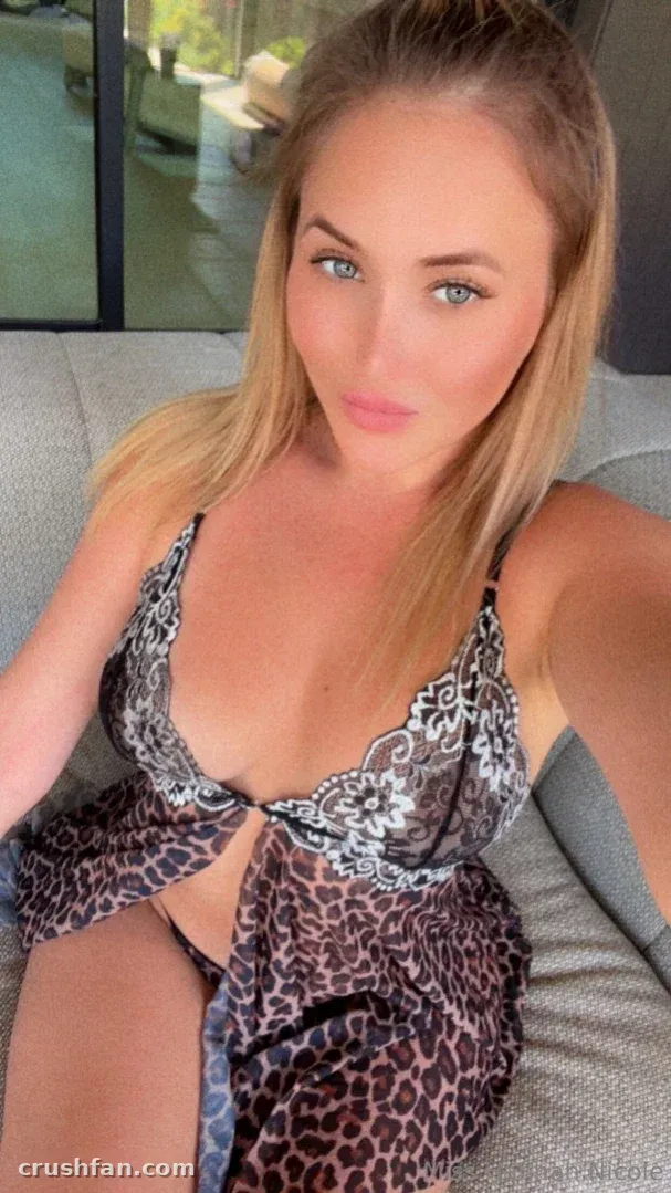 Hannah Nicole taking a selfie in leopard print lingerie on a grey sofa