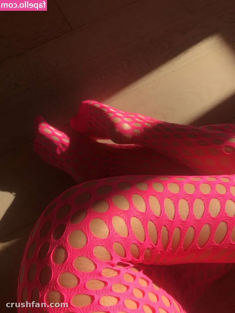 Pink patterned tights on crossed legs resting in a diagonal beam of sunlight indoors